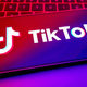 A photo of a smartphone laying on a keyboard shows the TikTok logo on the front.